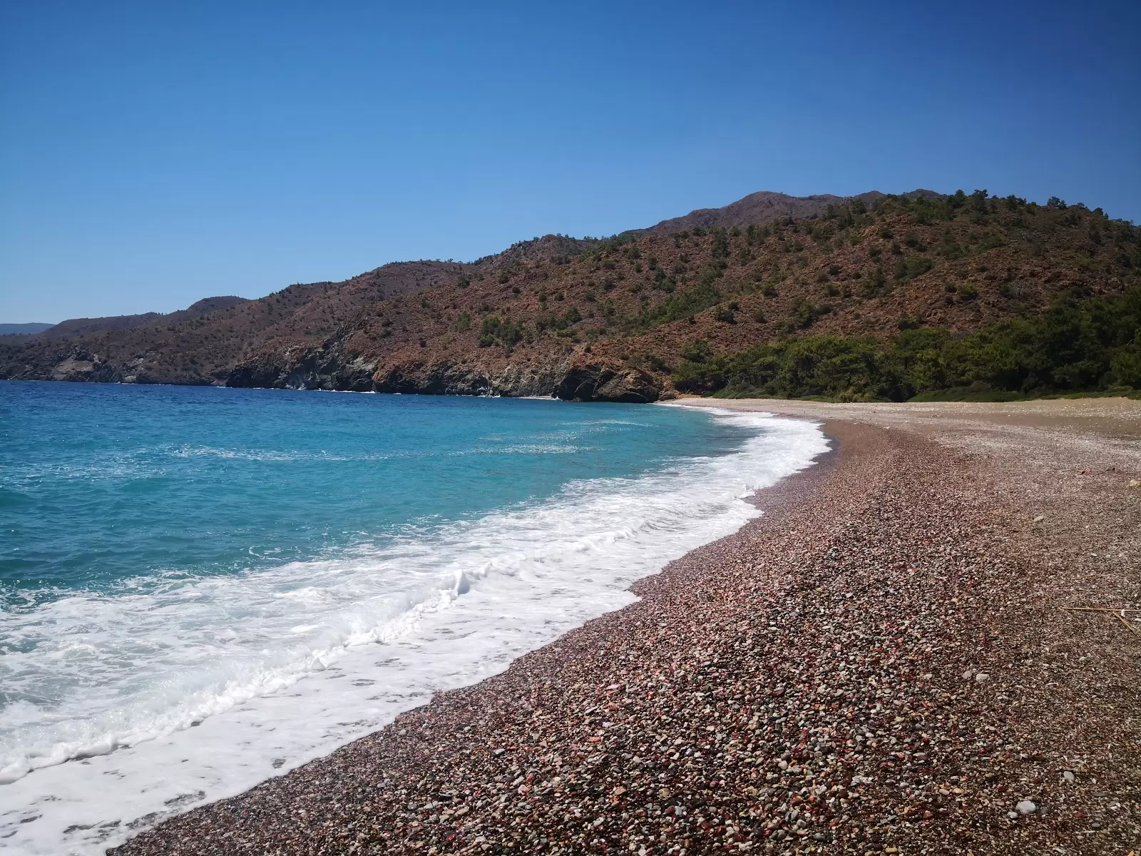 Dunkler Strand mit rosa Kieselsteinen